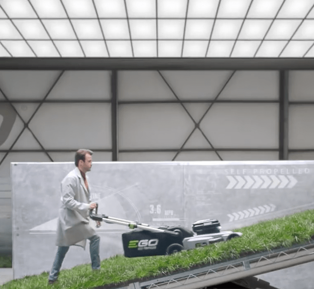 A man in a lab environment testing an EGO Mower on a steep incline. 